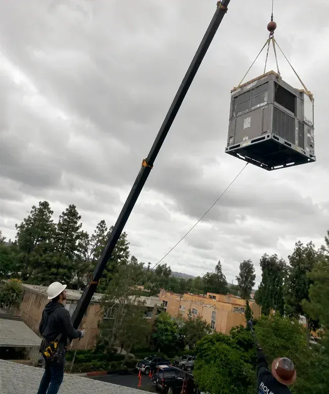 Crane lifting a large commercial HVAC unit during rooftop installation in Camarillo, CA