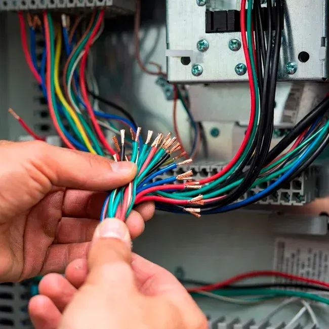 Electrician hands holding stripped colorful wires during electrical panel installation and wiring in Simi Valley, CA. Professional home electrical work.