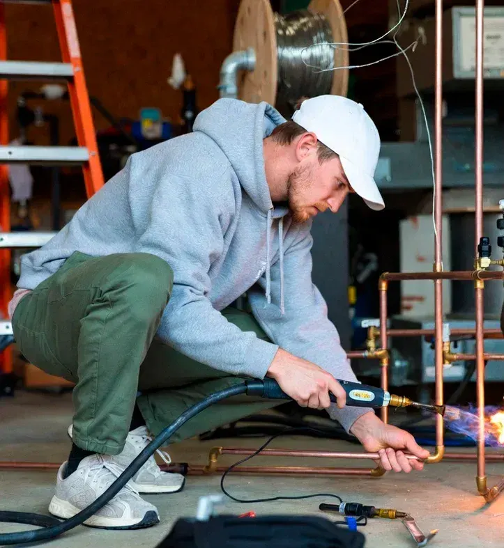 Professional HVAC technician brazing copper refrigerant lines with oxy-acetylene torch in Simi Valley