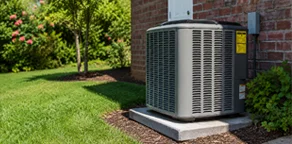 Modern heat pump unit installed outdoors next to a residential house with green lawn