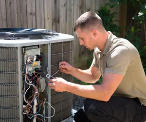 Professional HVAC technician performing electrical diagnostics and repair on outdoor air conditioning unit in Van Nuys, California