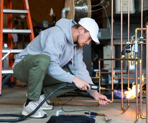 Professional HVAC technician brazing copper refrigerant lines with oxy-acetylene torch in Simi Valley