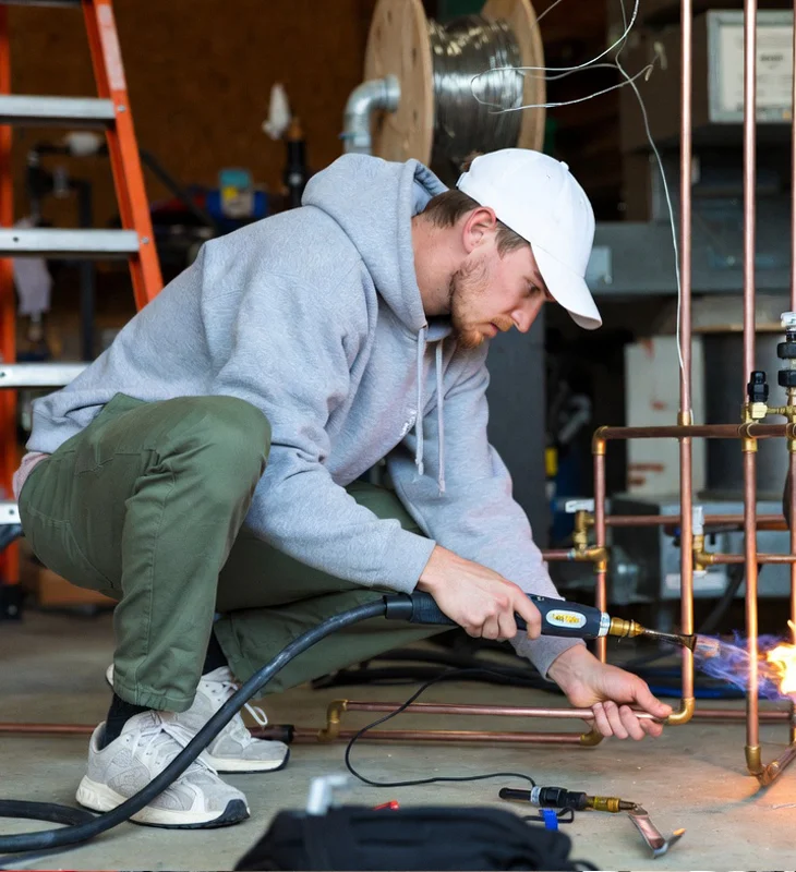 Professional HVAC technician brazing copper refrigerant lines with oxy-acetylene torch in Simi Valley
