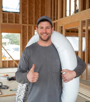 Friendly HVAC technician holding flexible duct and giving thumbs up at new home construction site in Van Nuys, California